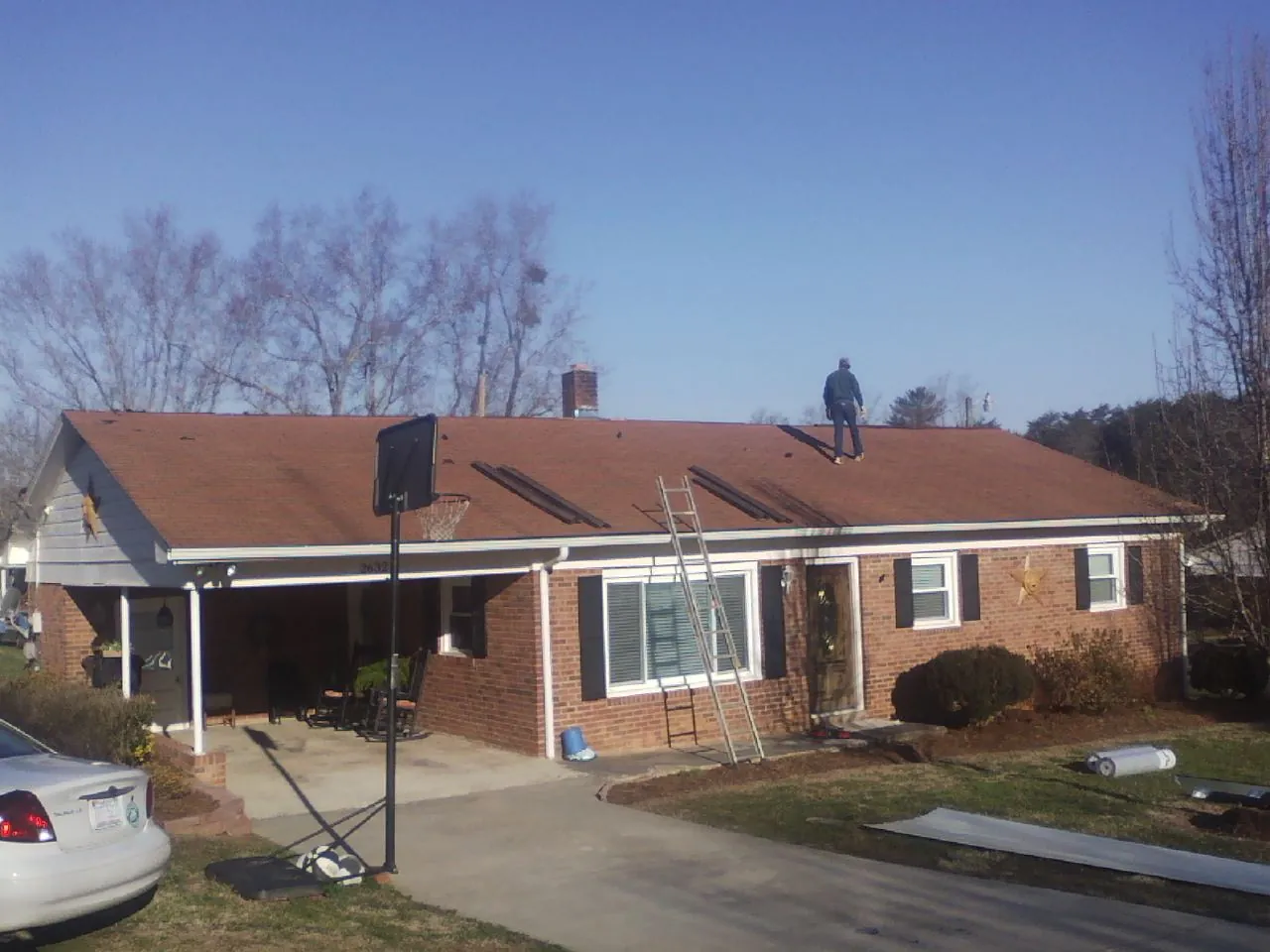 Roofer stripping a shingle roof on a brick ranch before metal panels in Skamokawa