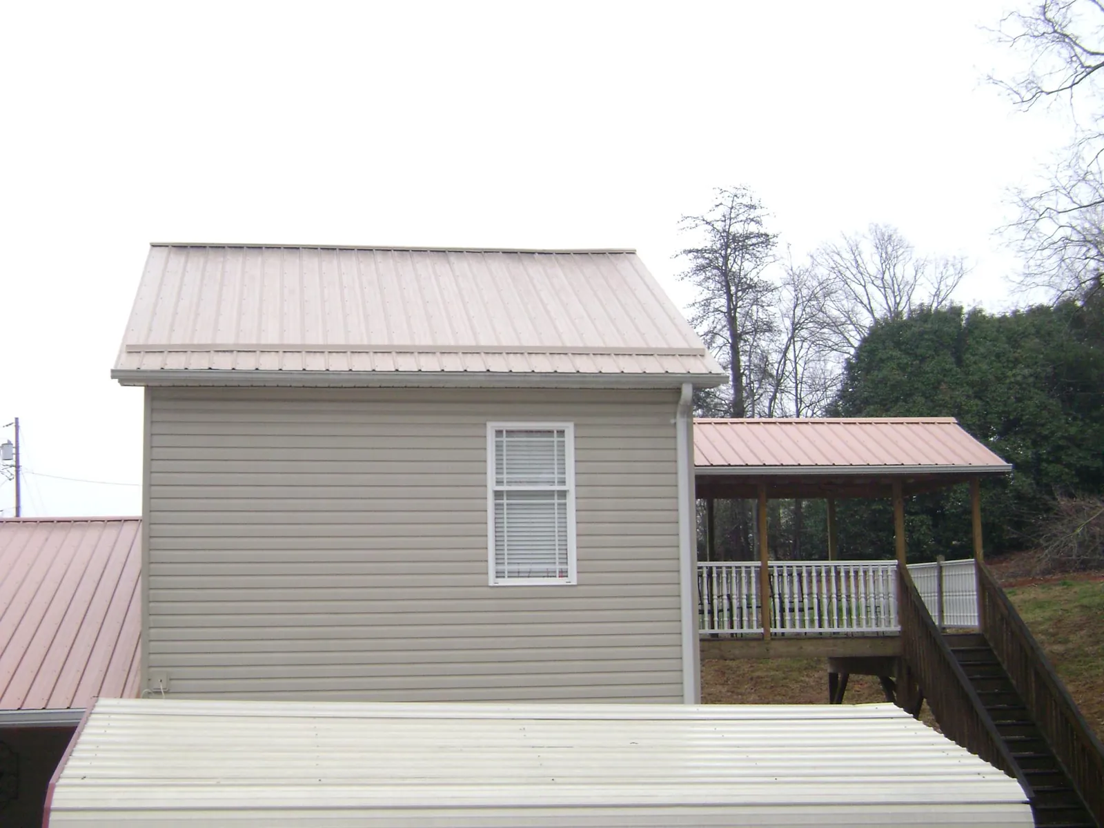 Tan metal roofs on a two story addition and attached porch, from a Roof Replacement job in Skamokawa