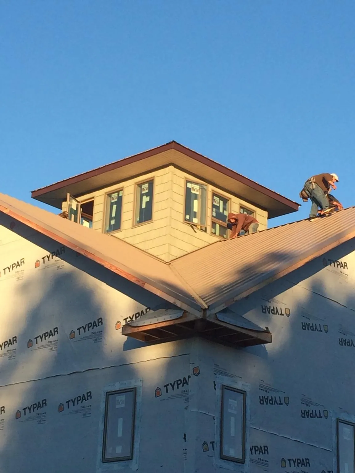 Roofers working around a rooftop cupola on a new metal roof at sunset — Roof Waterproofing in Skamokawa by Roofing Brothers